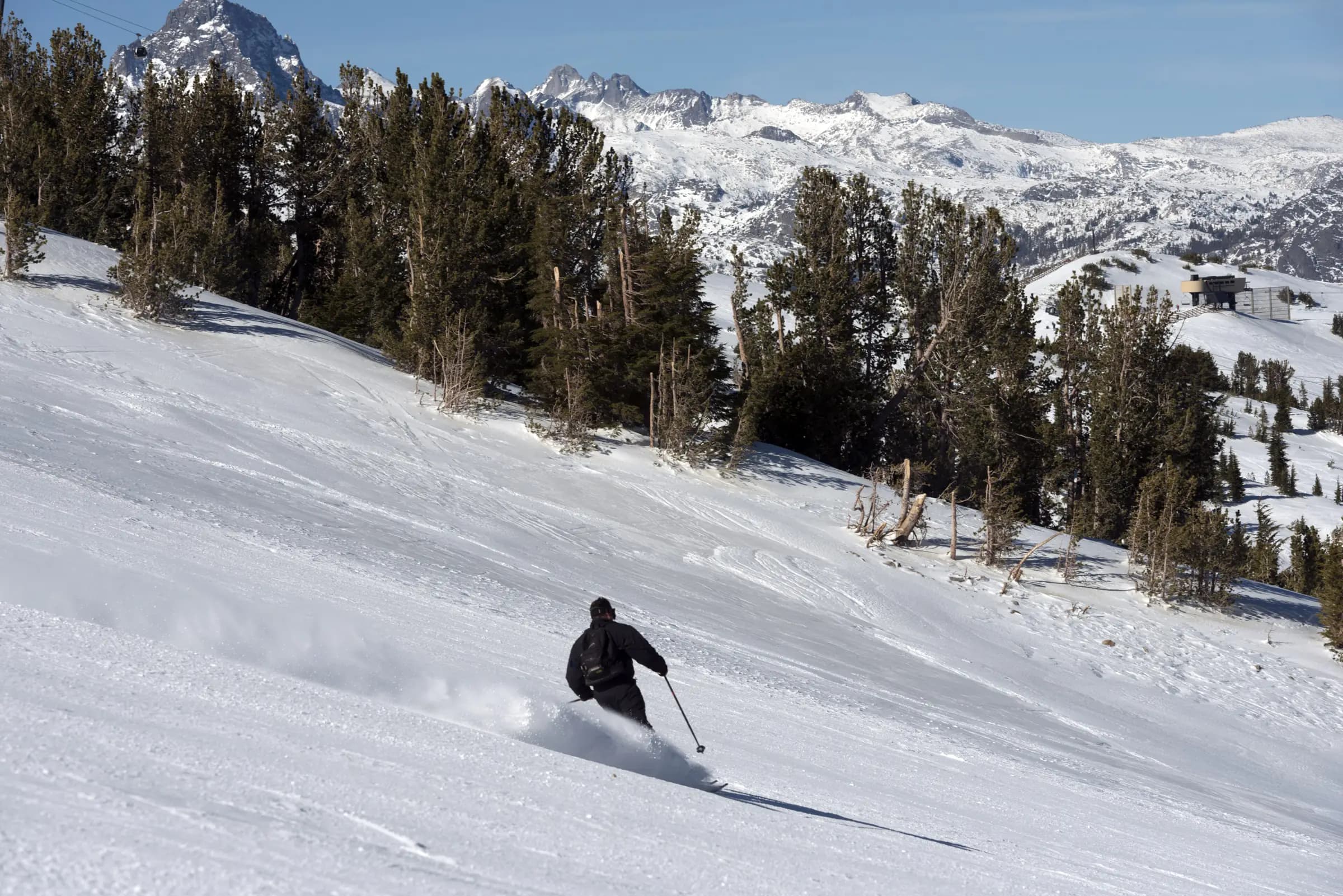 A skier carving fresh snow below the peaks at Mammoth Mountain, California